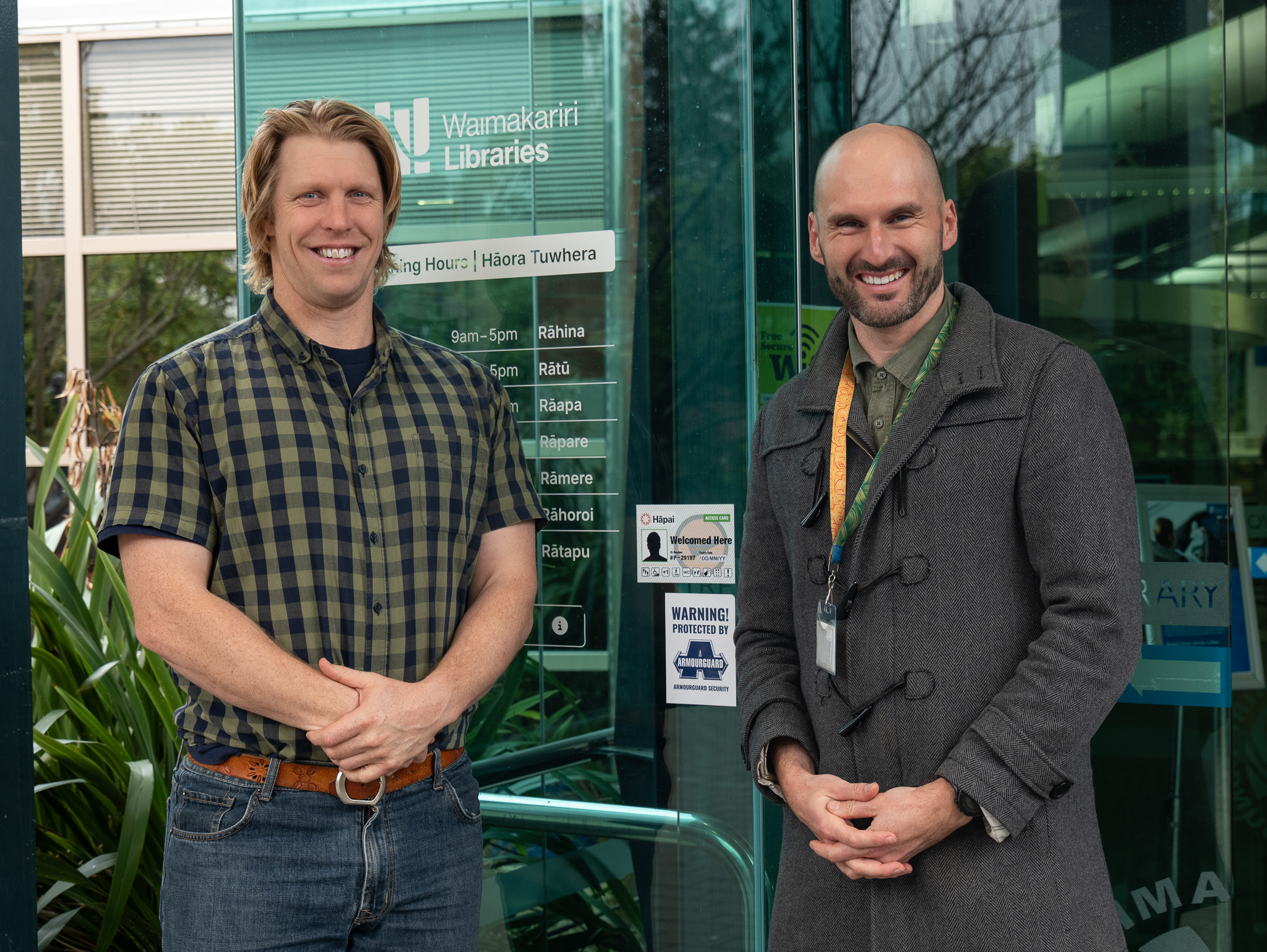 two men stand in front of library entrance smiling